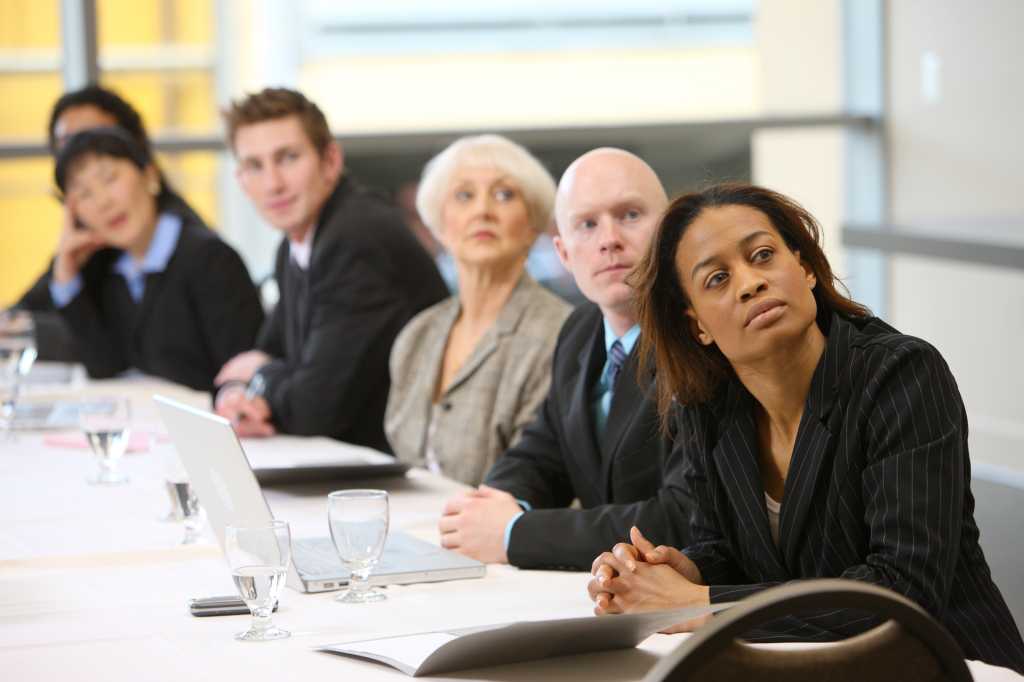 Businesspeople watch presentation in board room