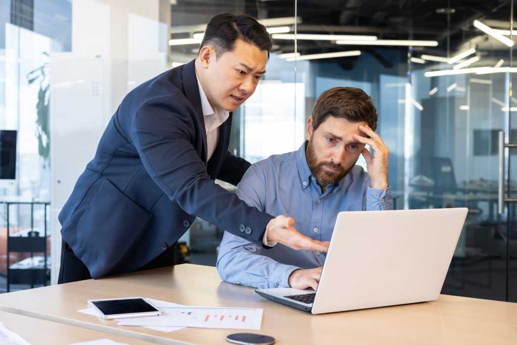 Two corporate professionals working together to resolve an issue, in a bright and modern office setting.