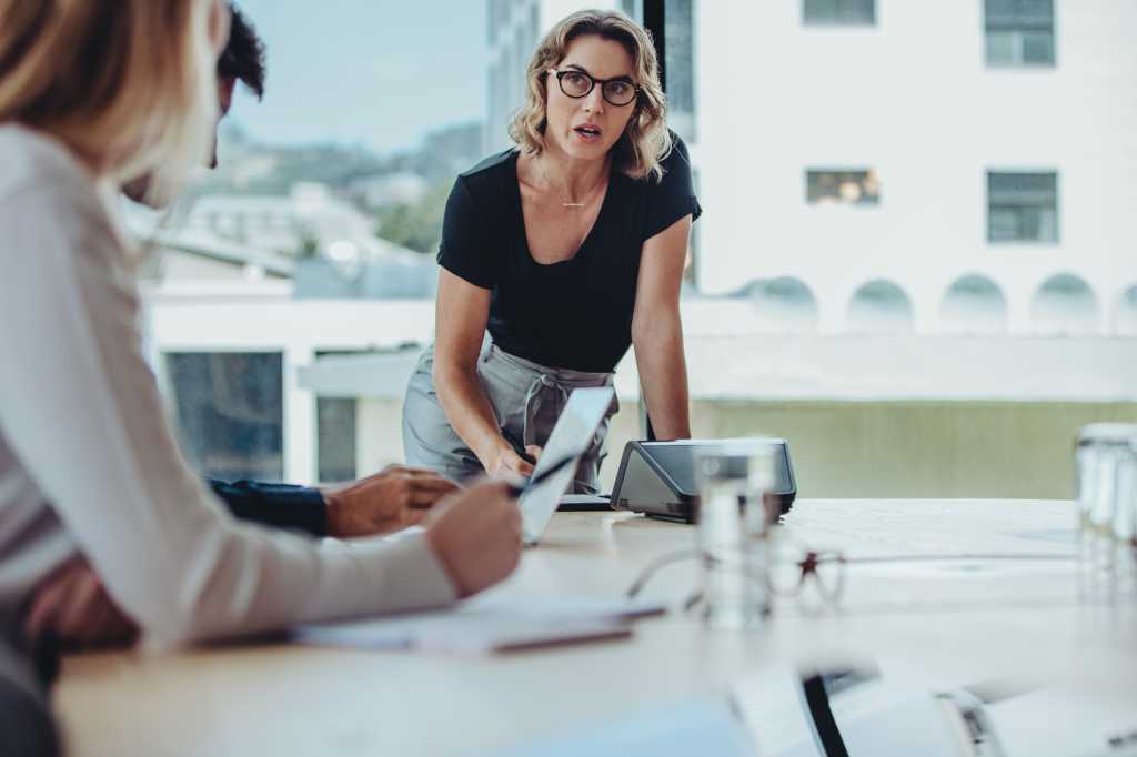 Woman explaining new strategies to coworkers during meeting. Businesspeople meeting in office board room for new project discussion.