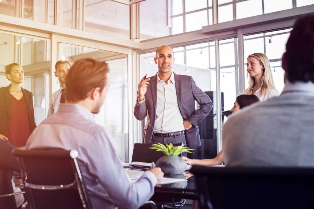 Senior man talking to employees in office meeting. Marketing team discussing new ideas with manager during a conference. Senior leadership training future businessmen and businesswomen.